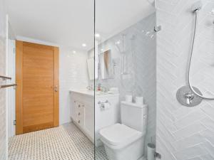 a white bathroom with a toilet and a shower at First Point Down by Discover Stradbroke in Point Lookout +13 photos