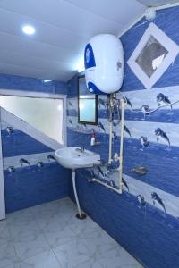 een blauwe badkamer met een witte wastafel en een watertank bij Om Niwas Homestay in Shimla