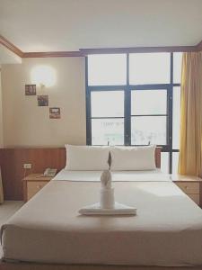 Schlafzimmer mit einem weißen Bett und einem großen Fenster in der Unterkunft Wantana Mansion in Hat Yai