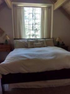 a bedroom with a large white bed with a window at The Storybook Cottage in Mendocino