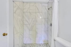 a bathroom with a shower with white tiles at Atlantis Inn - Tybee Island in Tybee Island