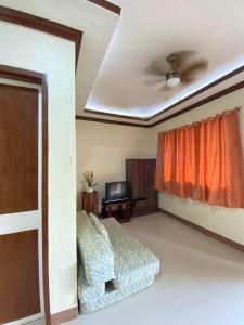 a living room with a bed and a window at Merangie Travellers Inn in Dauis