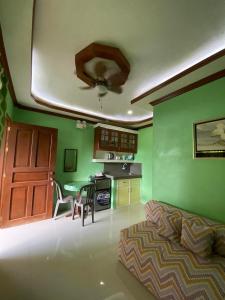 a living room with green walls and a bed and a kitchen at Merangie Travellers Inn in Dauis