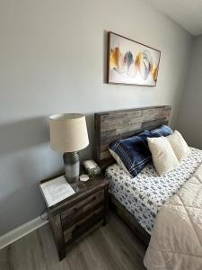a bedroom with a bed and a table with a lamp at Spotless 2 Bedrooms Suite 2 in Winnipeg in Winnipeg