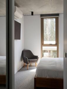 a bedroom with a bed and a chair and a window at 'Modern Minimalism' Slate Chic in the City in Melbourne