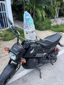 una moto nera parcheggiata accanto a una borsa della spesa di Posada Sunrise View a Providencia