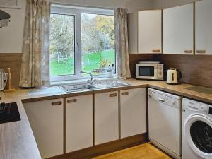 a kitchen with a sink and a microwave and a window at Barr Beithe Lower in Dallavich