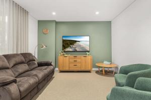 Una sala de estar con un sofá y un televisor de pantalla plana. en Splash by Experience Jervis Bay, en Huskisson