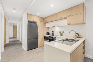 a kitchen with wooden cabinets and a stainless steel refrigerator at Splash by Experience Jervis Bay in Huskisson