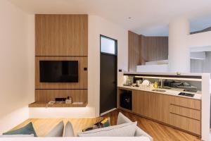 Impiana by Roxy Hotel في كوتشينغ: غرفة معيشة مع مطبخ وتلفزيون