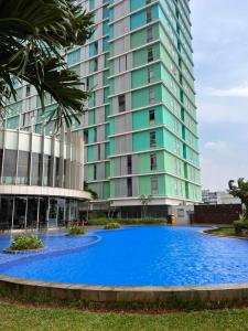 ein großes Gebäude mit einem blauen Pool davor in der Unterkunft Pejaten Park Residence in Jakarta
