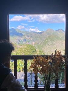 una persona mirando por una ventana a una montaña en Ma Pi Leng homestay en Làng Xao Vang