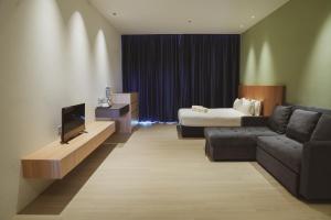 Habitación de hotel con sofá, cama y TV en Roxy Beach Apartment, en Sematan