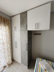 Schlafzimmer mit weißen Schränken und einem Bett in der Unterkunft BlueLine apartment 3 in Loutraki