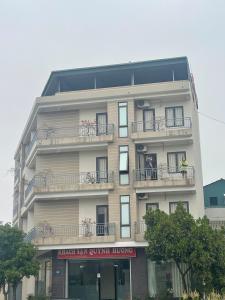 wysoki biały budynek z ludźmi na balkonach w obiekcie Quỳnh Hương Hotel Phú Thọ w mieście Phú Thọ