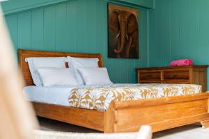 Bett in einem grünen Zimmer mit einem Bettrahmen aus Holz in der Unterkunft Leu Boucan in Saint-Leu