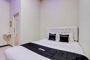 a white bedroom with a large bed with black pillows at Capital O 93244 Angkasa Inn in Tegal