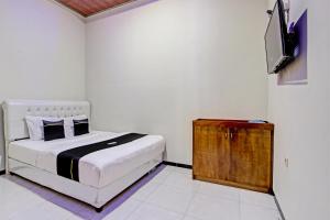 a bedroom with a bed and a flat screen tv at Capital O 93244 Angkasa Inn in Tegal