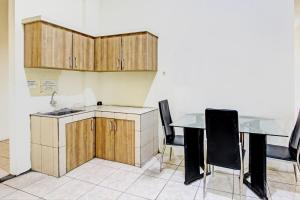 a kitchen with wooden cabinets and a table and chairs at Capital O 93244 Angkasa Inn in Tegal