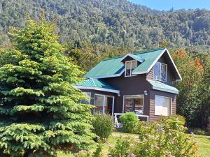 a house with a green roof and a tree at Refugio y tinajas Vientos del lago in Los Riscos