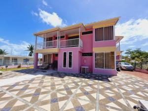 a pink house with a car parked in front of it at Posada Seven Colours Ocean in Providencia
