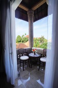 a balcony with tables and chairs and a large window at Guildwood Villa Bali in Sanur