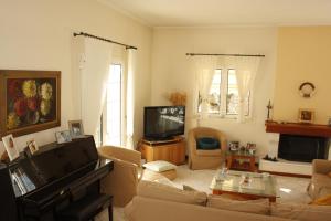 ein Wohnzimmer mit einem Sofa und einem TV in der Unterkunft House Angie in Porto Rafti