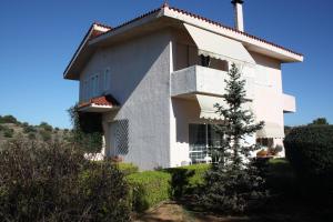 ein weißes Haus mit einem Baum davor in der Unterkunft House Angie in Porto Rafti