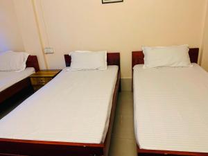 2 bedden in een kamer met witte lakens en kussens bij OYO Flagship Hotel West End in Darjeeling