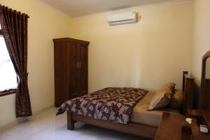 a bedroom with a bed and a wooden cabinet at Griya Hanna in Yogyakarta