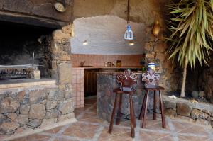 een keuken met twee houten krukken naast een stenen muur bij Castillo Lanzarote Villa 1 - Sleep in a Volcanic Cave in Tías