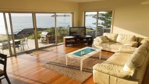 sala de estar con sofá, mesa y TV en Jones Beach House, en Kiama Downs