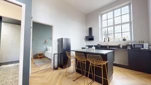 a kitchen with a black counter and a refrigerator at Le porte plume in Dole