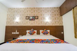 a bedroom with a large white bed with colorful pillows at FabHotel Shiva Grand in Coimbatore