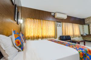 a bedroom with a large bed and a chair at FabHotel Shiva Grand in Coimbatore