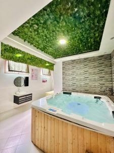 Atmosphere Hotel & Spa في أنتاناناريفو: حمام مع حوض كبير مع سقف أخضر