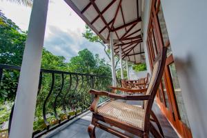 einen Balkon mit Schaukelstühlen und Bäumen in der Unterkunft Ciel Grand Villa in Kandy