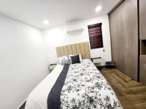 1 dormitorio con 1 cama con manta blanca y negra en * Elegante * Departamento Pitagoras 4, en Ciudad Juárez