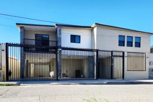 een wit huis met een zwarte poort bij * Elegante * Departamento Pitagoras 4 in Ciudad Juárez