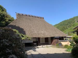 una casa con techo de paja y patio en KANAU, en Gojō