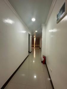 a hallway with a white wall and a red trash can at PUNTA CLARK HOTEL in Clark