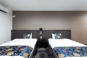 ein Zimmer mit 2 Betten und einem Nachttisch dazwischen in der Unterkunft ホリディパールホテル in Osaka