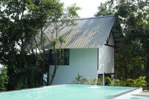a house with a swimming pool and a building with a metal roof at SaffronStays Aranya Vilas & Raanwaara Cottage in Āmbavna