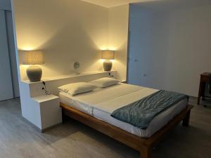 a bedroom with a bed with two lamps on it at Puunui Lodge in Vairao