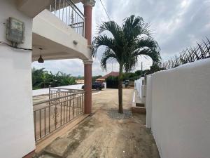 a palm tree in front of a house with a fence at Sigma Theta Homes - Kumasi Atimatim in Kumasi