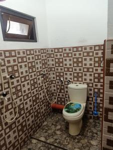 a bathroom with a toilet with a tiled wall at Beach Guest House Addalaichenai in Addalachenai