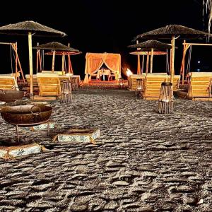 哈拉奇的住宿－Alia Luxury Beachfront Suites and SPA，一群椅子和遮阳伞在晚上在海滩上