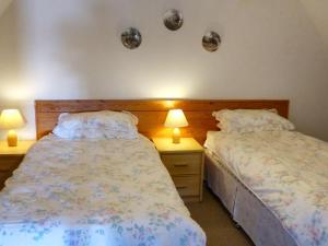 two beds in a bedroom with two lamps on tables at The Stable in Dalavich
