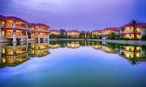 a row of houses at night next to a body of water at Regency Lagoon Resort in Rajkot