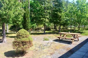 una mesa de picnic de madera en un parque con un arbusto en Charming Cottage Close To The Beach, en Vester Sømarken
